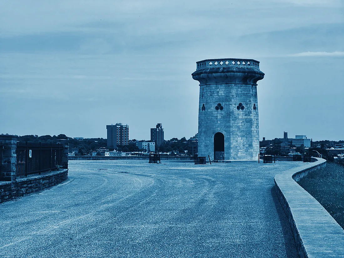 A stone tower above Baltimore with the city skyline behind it, rendered in deep blue